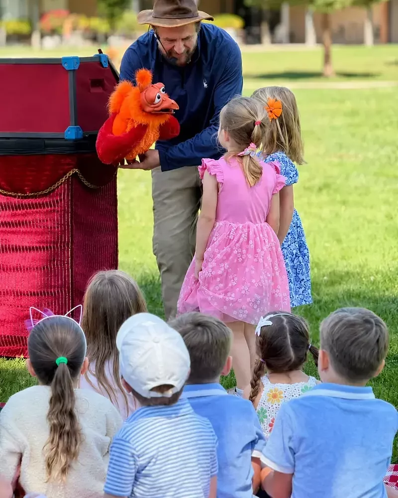Jungle Joe performing an outdoor puppet show for children on a school field in Fremont, CA