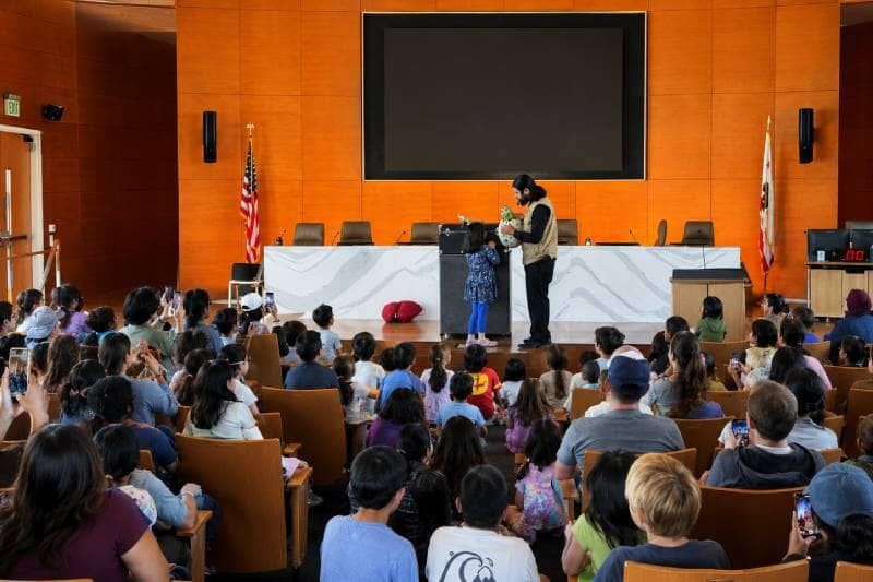 Children reacting to interactive dinosaur puppet at library Dinovember program